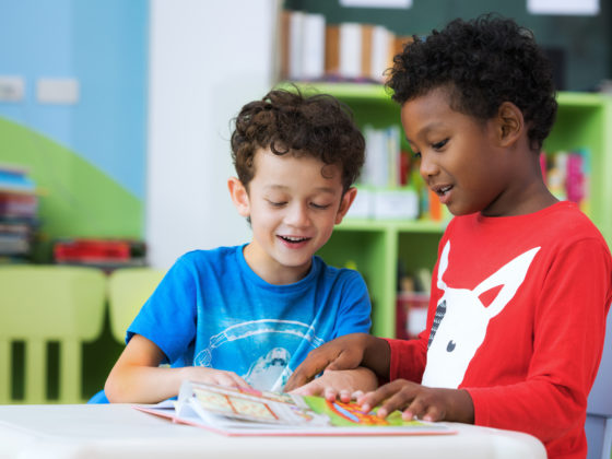 Two boys looking at a book together in class.