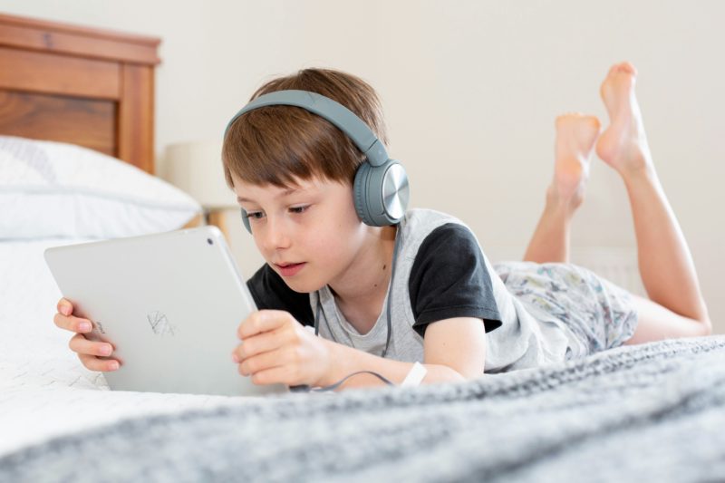 Boy with headphones enjoying the Read-to-Me books on the Epic app in his bed