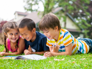 Three children reading a book together outdoors, representing fun summer reading activities for kids with Epic Books for Kids.
