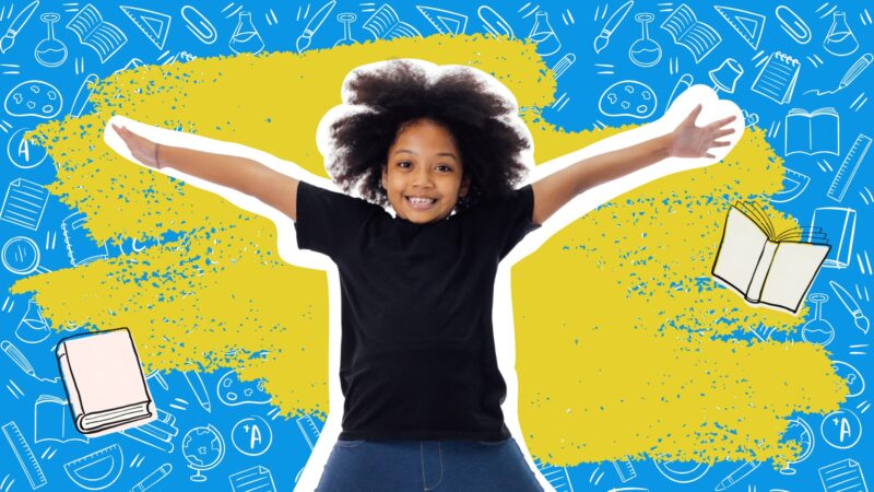 Smiling child with arms outstretched in front of a blue background covered in school supply doodles